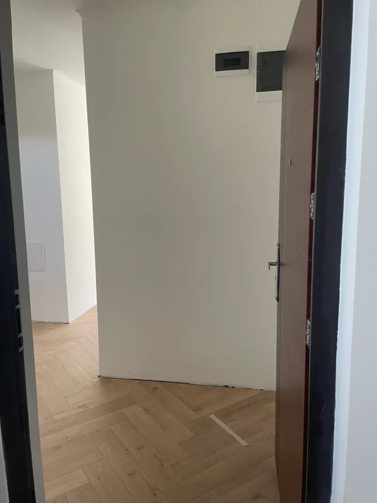 Tágas, világos helyiség, ajtó előtti nézetből