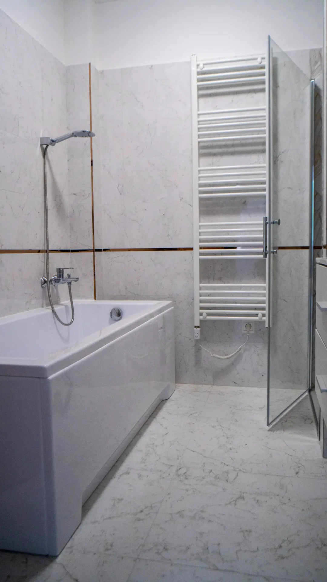 Fehér fürdőkád és törölközőszárító radiátor